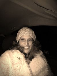 Portrait of smiling young woman wearing fur coat in car at night