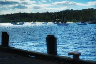 Sailboats moored on sea against sky