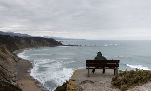 Man with cap looks at the horizon in a beautiful landscape with sea and mountains.