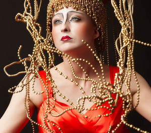 Young woman in bead headwear against black background