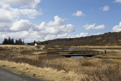 Thingvellir national park  with a visitor walking away from small bridge and thingvallakirkja church