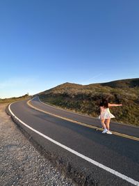 Scenic view of coastal road and the back of a girl
