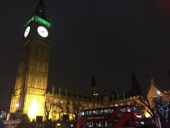 Low angle view of clock tower at night