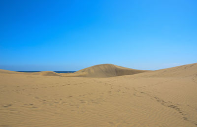 Scenic view of desert against clear blue sky