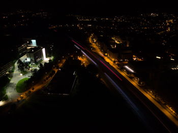 High angle view of illuminated street amidst buildings in city at night