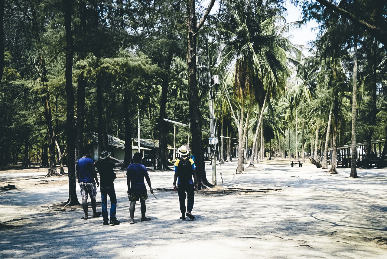 REAR VIEW OF PEOPLE WALKING ON STREET AMIDST TREES