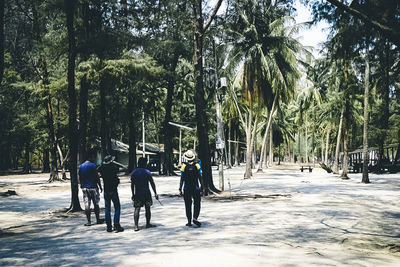 Rear view of people walking on palm trees