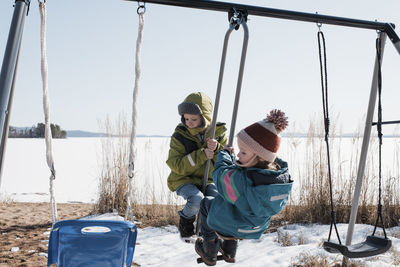 Kids playing on a double swing together by the ocean in sweden