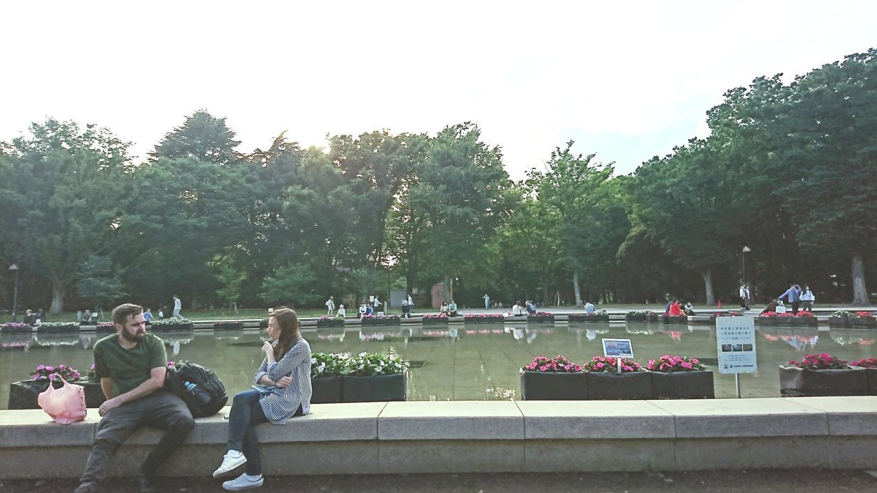 tree, large group of people, real people, sitting, water, day, lifestyles, men, outdoors, women, nature, sky, togetherness, beauty in nature, people