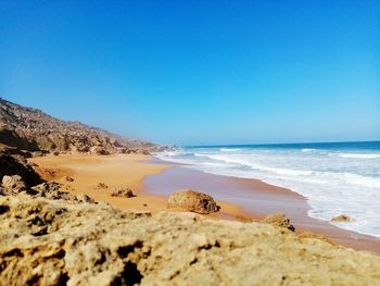 Scenic view of beach against clear blue sky