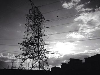 Low angle view of power lines against cloudy sky