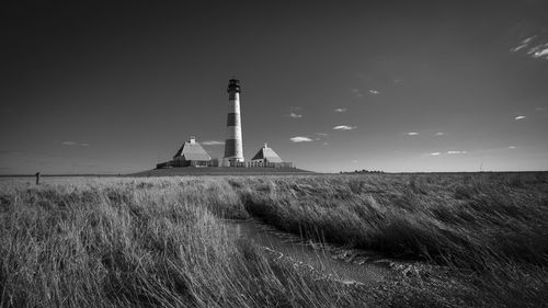 Lighthouse on field against sky