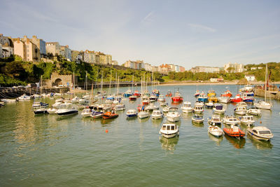 Sailboats moored in harbor against buildings in city