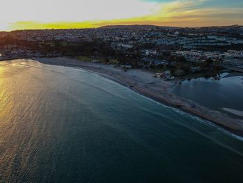 High angle view of townscape by sea against sky during sunset