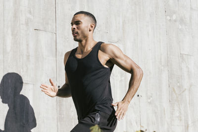 Upper part african american male athlete running against concrete wall person