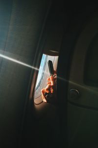 Cropped hands of woman photographing from mobile phone through airplane window