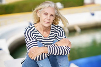 Portrait of young woman sitting on railing