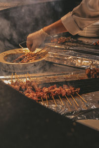 Close-up of person preparing food on barbecue grill