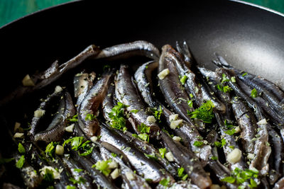 Fresh anchovies to be cooked in a pan with garlic and parsley. wood background.