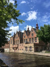 View of buildings by river against cloudy sky