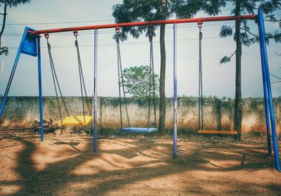 Empty swings in playground against sky