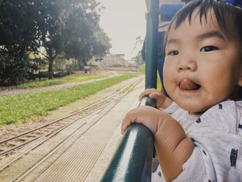 Portrait of boy on railroad track against sky