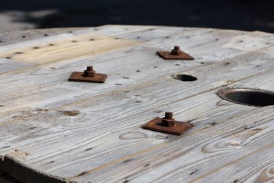 High angle view of rusty metallic bolts on wood