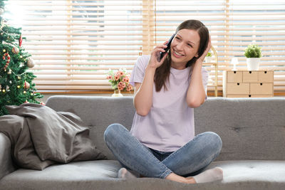 Portrait of young woman sitting on sofa at home