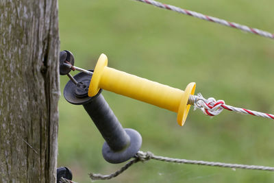 Close-up of padlock on rope against fence