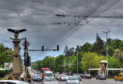 Cars on road against cloudy sky