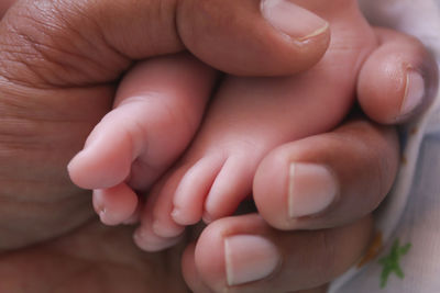 Close-up of father holding newborn baby legs 