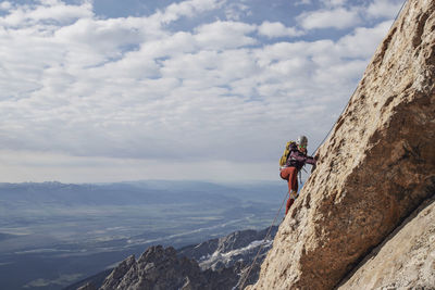 Roped female rock climber ascends a cliff in the tetons, wyoming