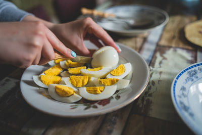 Cropped hands of woman cutting egg at table