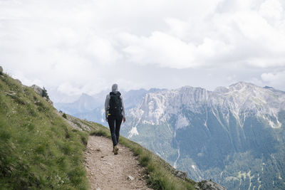 Rear view of woman walking on trail against mountain range