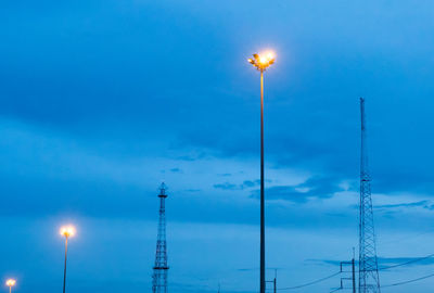 Low angle view of illuminated street lights against blue sky