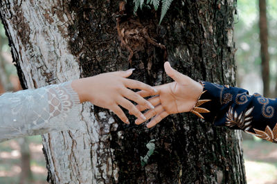 Midsection of woman holding tree trunk