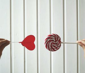 Cropped woman hands holding candies against white wall