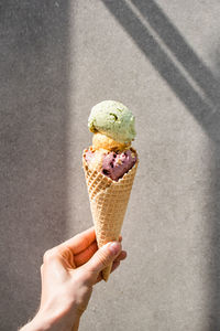 Multi-colored ice cream in a hand against a gray wall. summer food