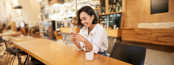 Young woman using mobile phone in cafe