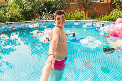 Full length of a smiling young man swimming in pool