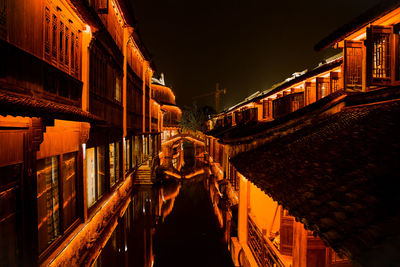 Illuminated street amidst buildings in city at night