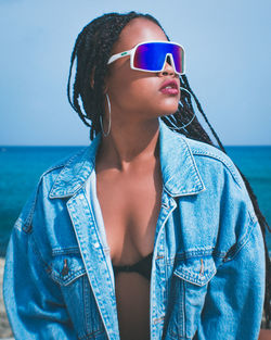 Young woman wearing sunglasses against blue sea