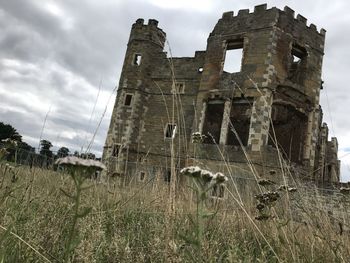Low angle view of old abandoned building on field against sky