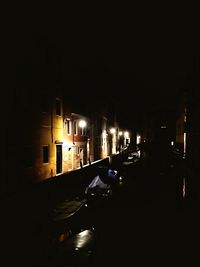 Cars on illuminated street amidst buildings in city at night