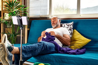 Handsome bearded man following online knit tutorial on his smartphone.