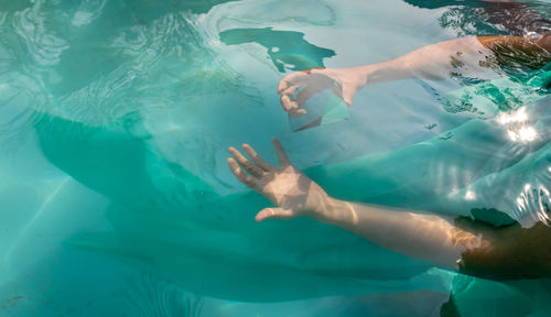 Cropped hands of woman holding prism in swimming pool