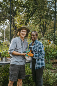 Portrait of smiling female and male farmers standing in garden