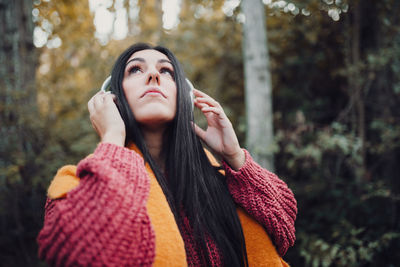 Young woman listening music with her headphones in the forest