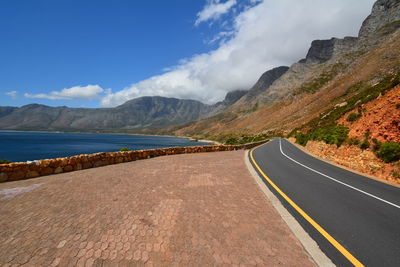 Road leading towards mountains against sky