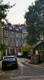 Cars on street by buildings against sky